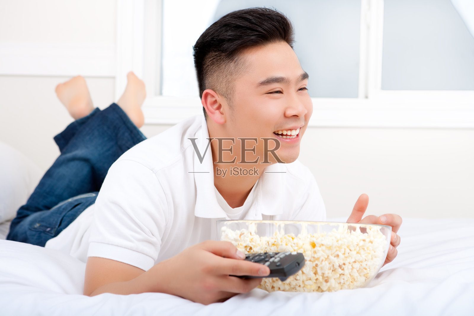 一个亚洲男人在卧室里吃爆米花照片摄影图片
