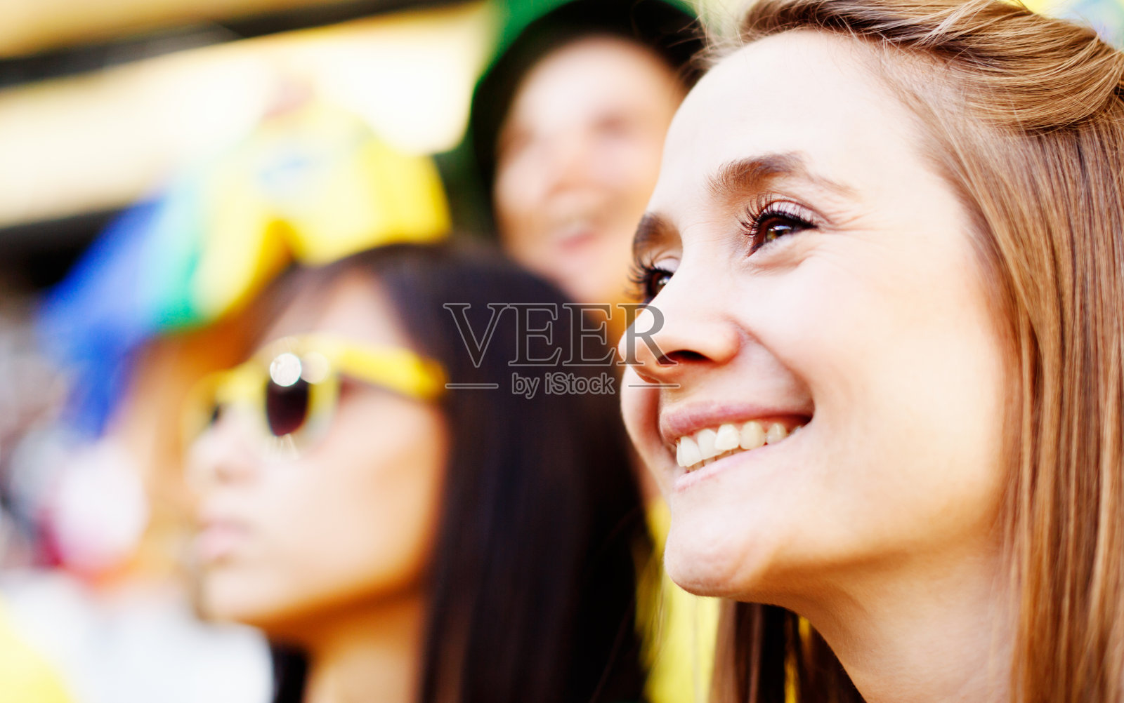 漂亮的金发球迷和朋友在足球比赛微笑照片摄影图片