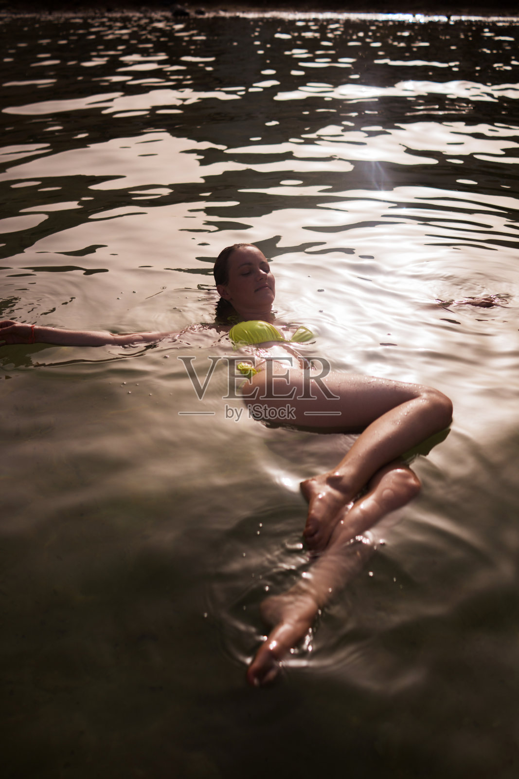 放松的女人漂浮在死海在夏天的白天。照片摄影图片