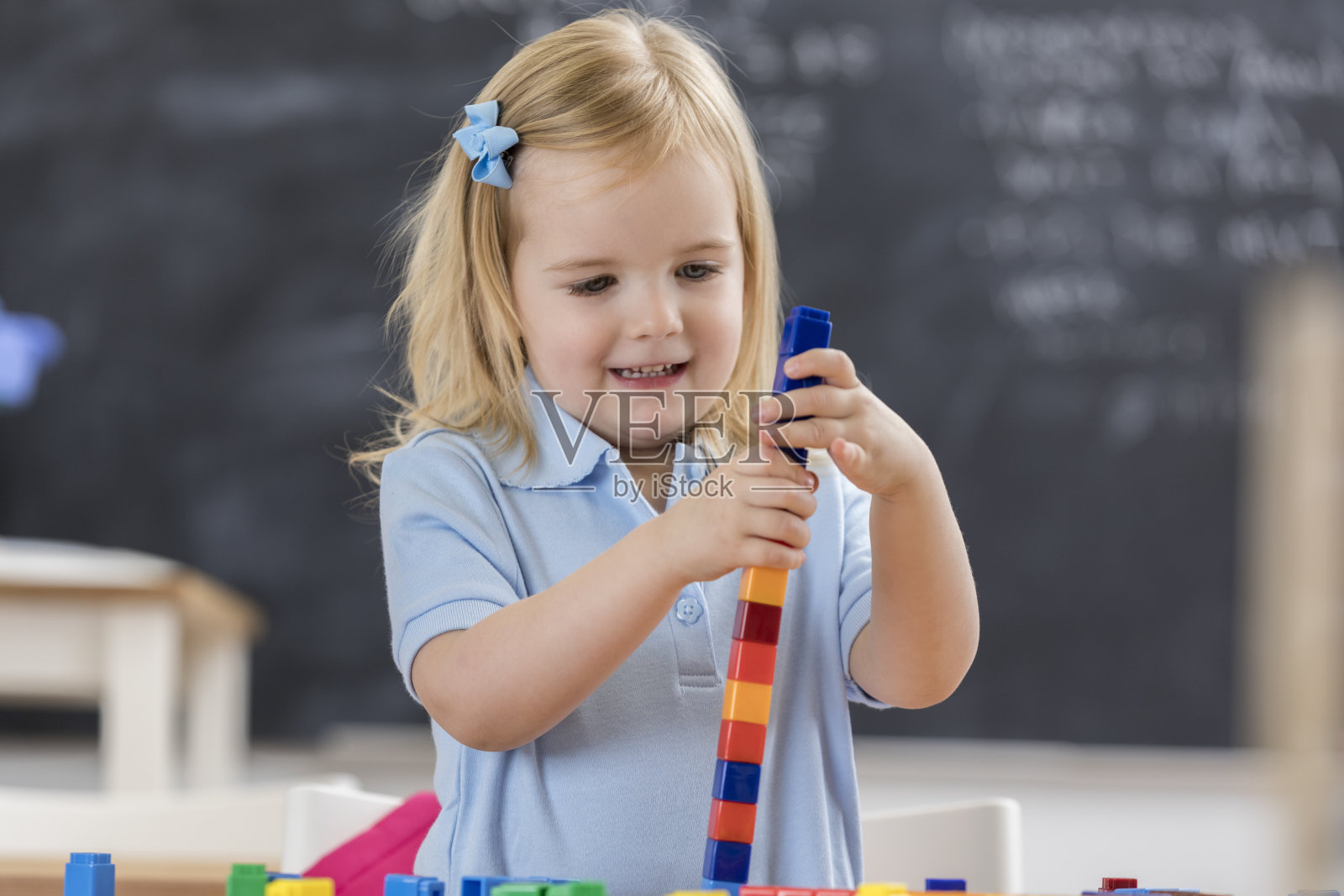 漂亮的学龄前女孩用塑料黑人搭了一座塔照片摄影图片