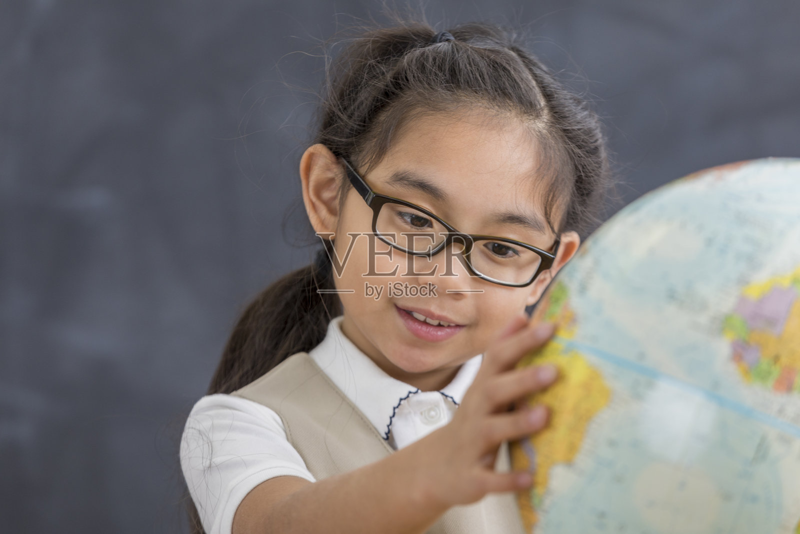 小女孩在学校看地球仪照片摄影图片