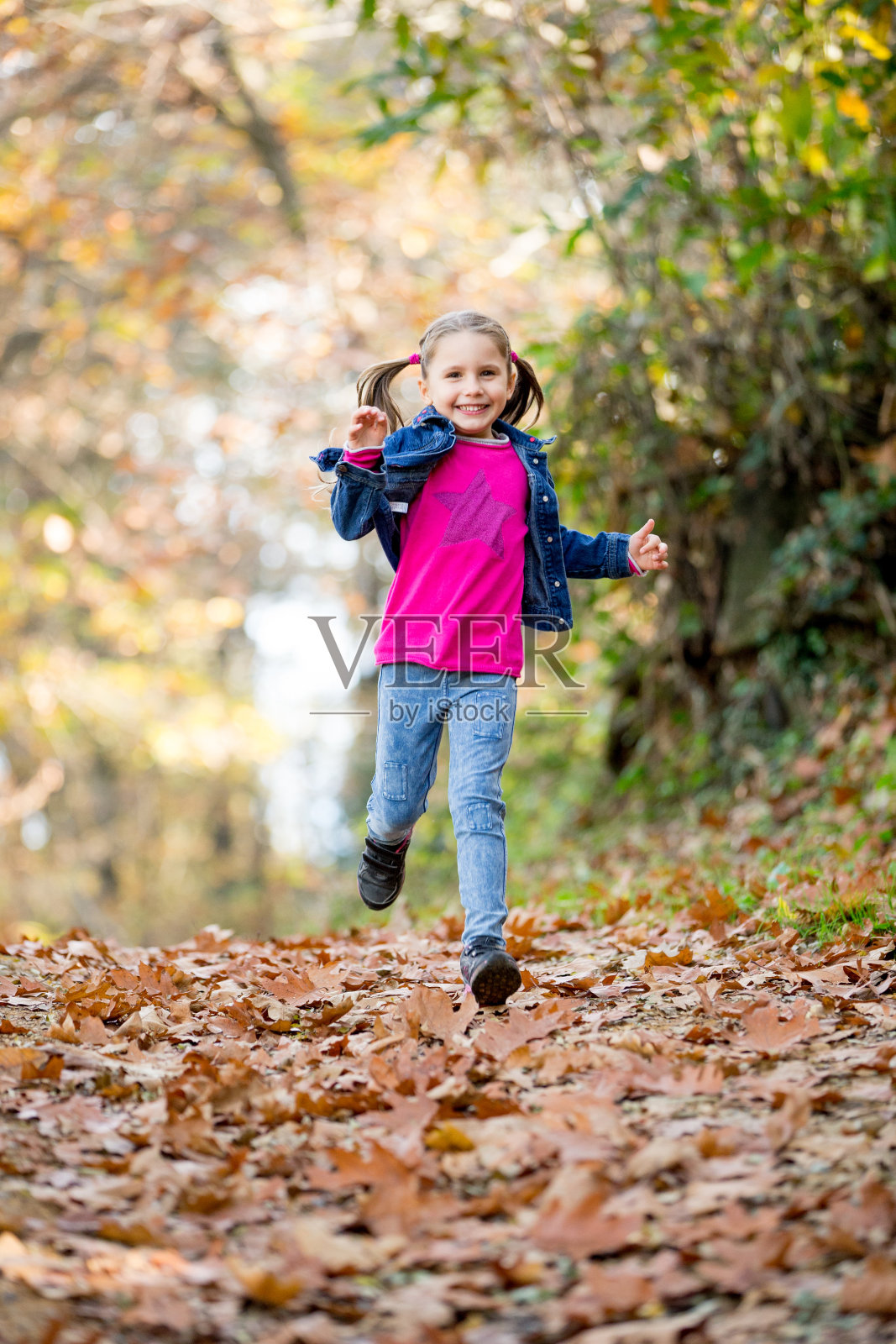 秋天里在森林里奔跑的快乐小女孩照片摄影图片