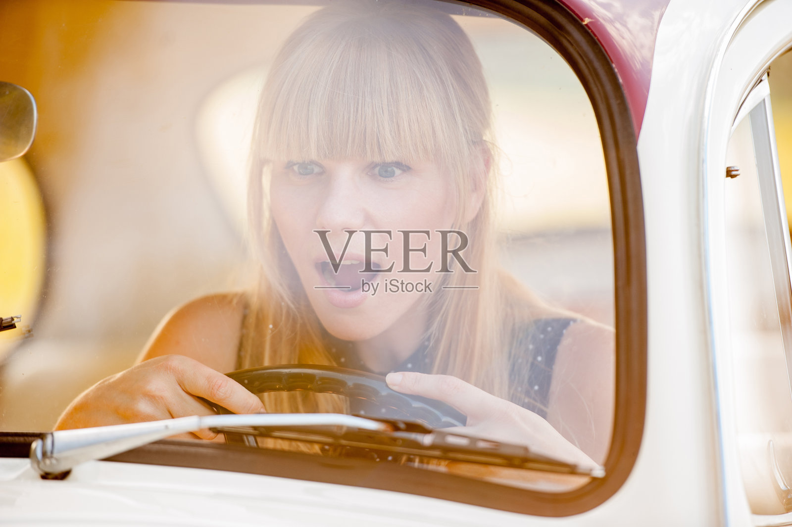 迷人的女人驾驶老爷车-透过窗户看照片摄影图片