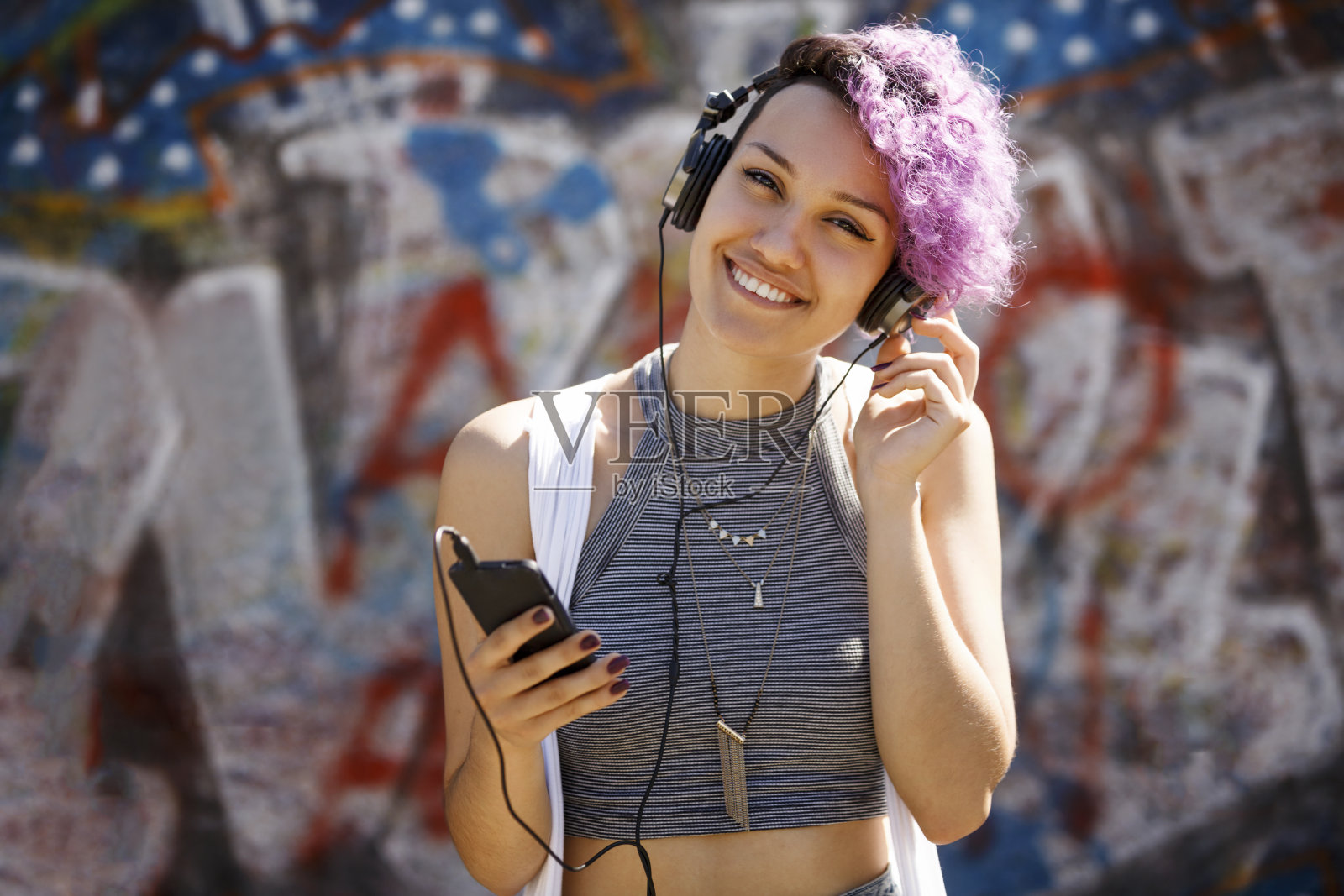 戴着耳机在户外听音乐的时髦女孩照片摄影图片