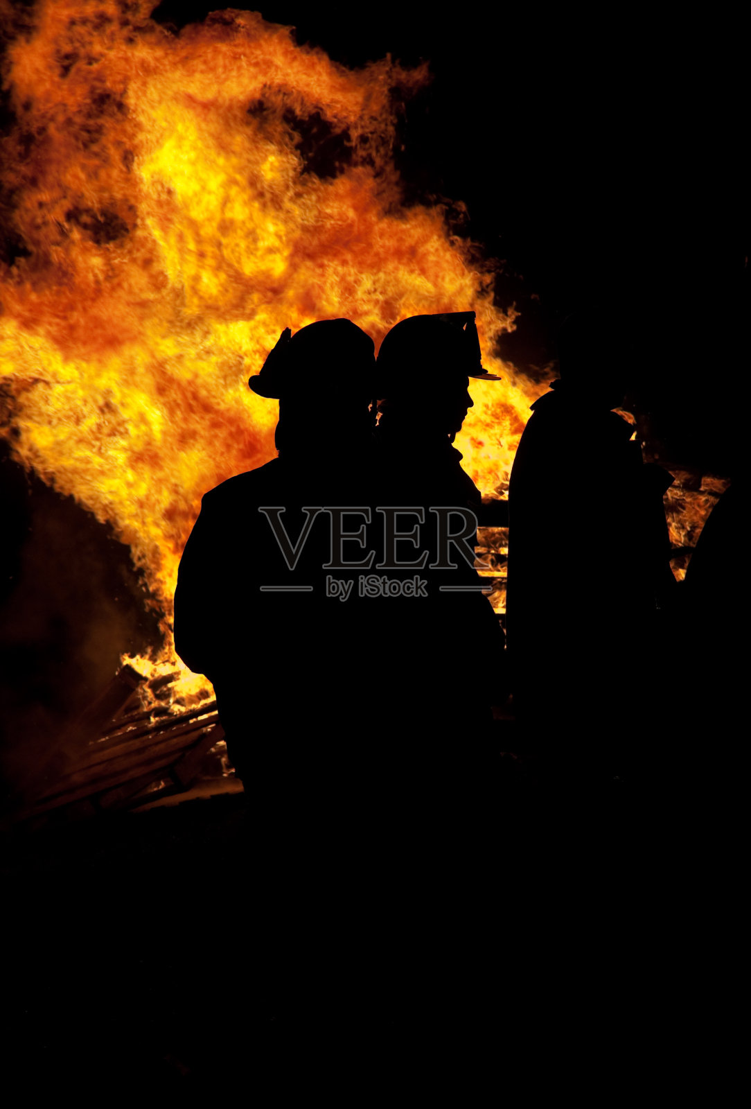 背景是消防员的剪影和火焰照片摄影图片