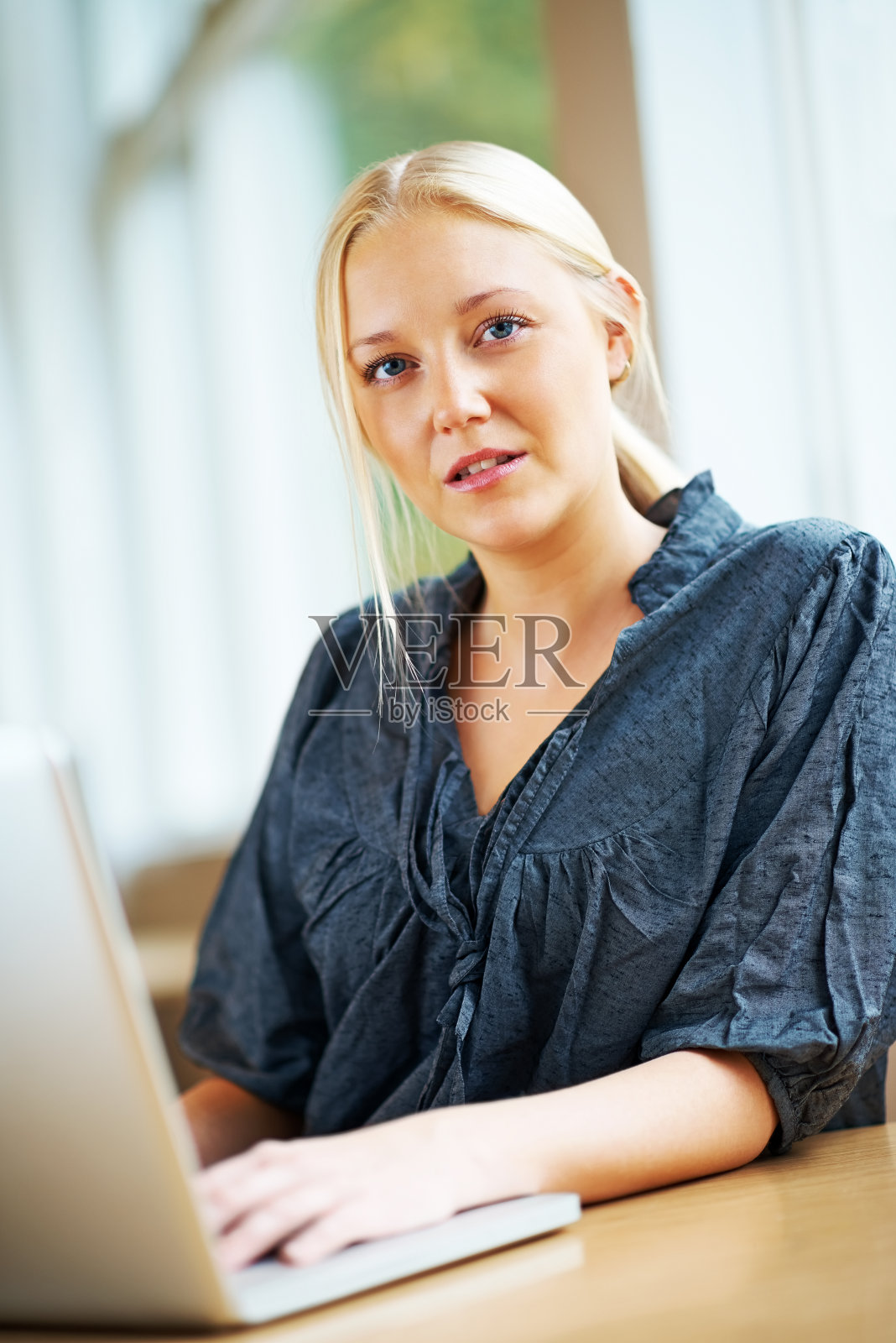 在笔记本电脑上工作的快乐金发女人照片摄影图片