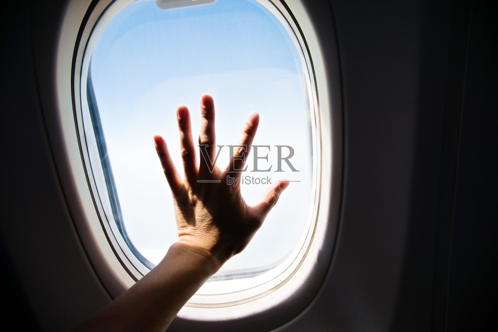 把手放在飞机窗户上照片摄影图片