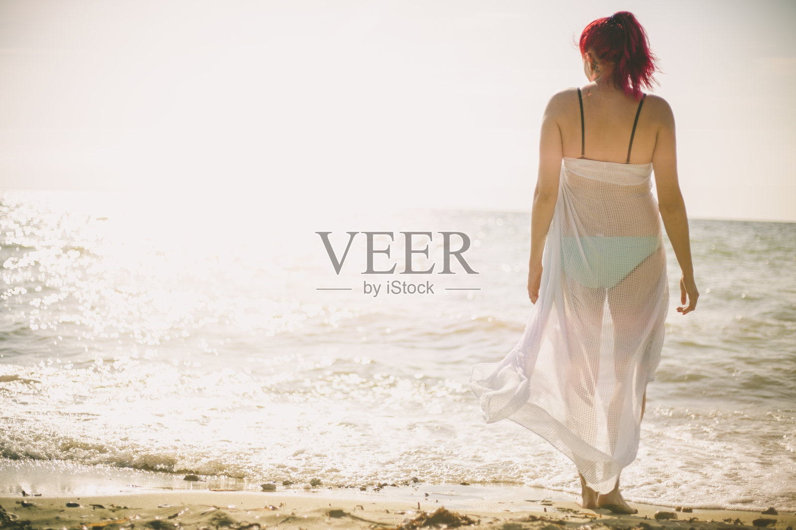 黄金时间，女人在沙滩上散步照片摄影图片