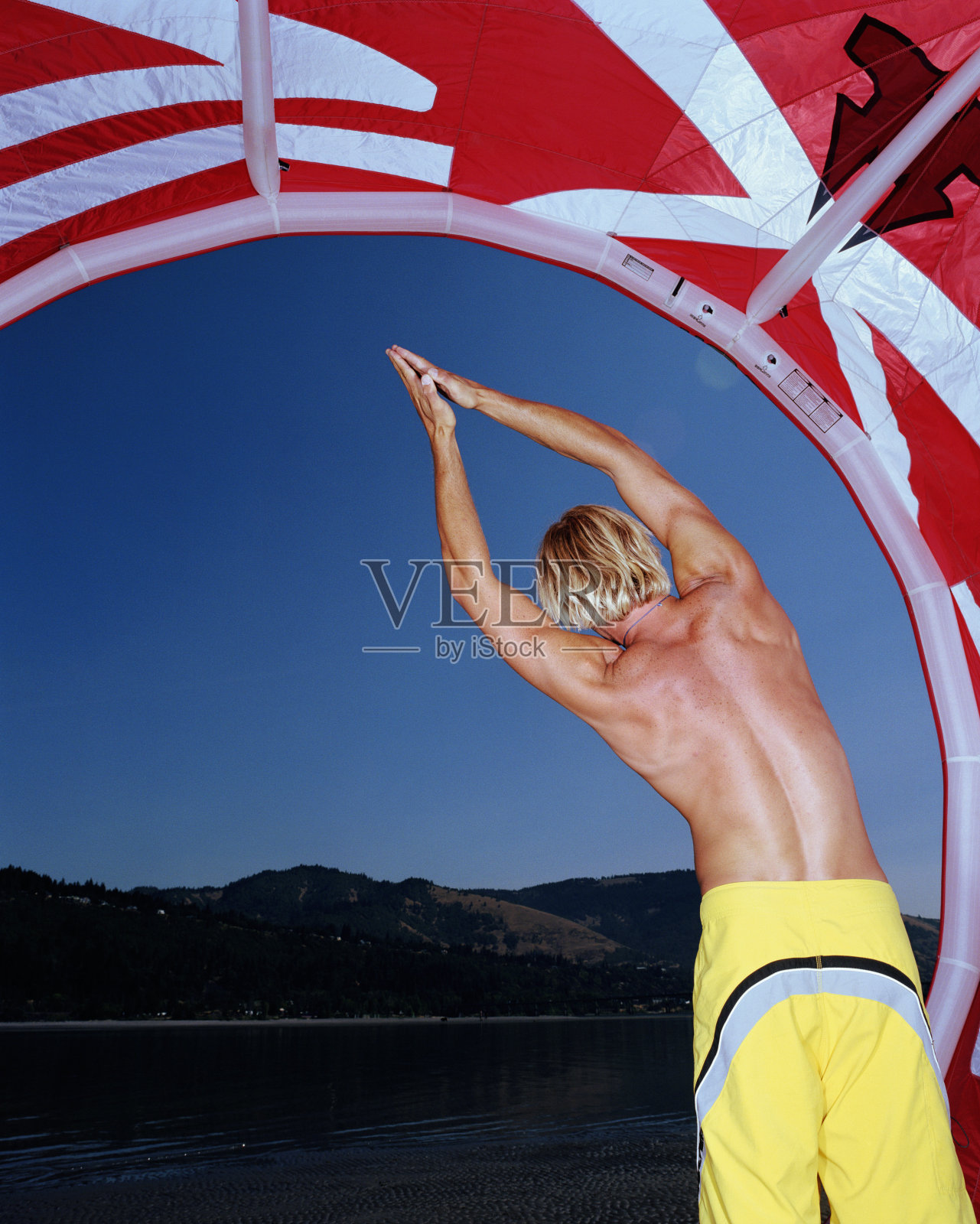 年轻人伸展在风筝板下的风筝，举起手臂，rea照片摄影图片