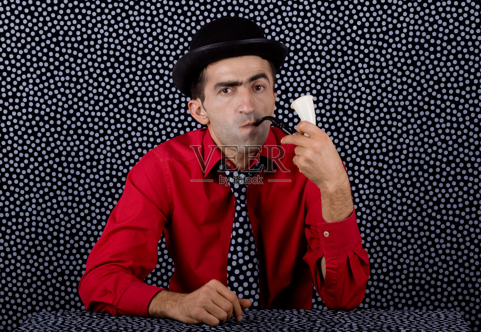 老式侦探在有斑点的背景下抽烟斗照片摄影图片