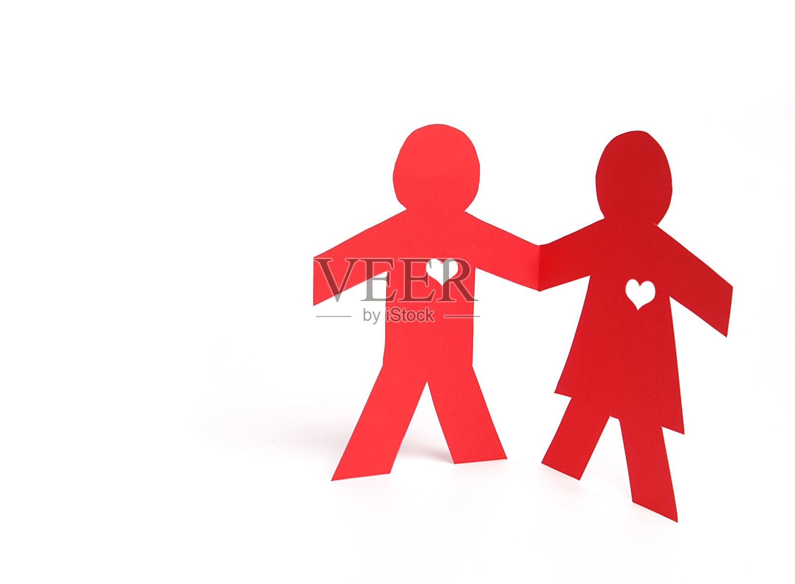 红纸上的人手牵着手，上面刻着白色的心。照片摄影图片