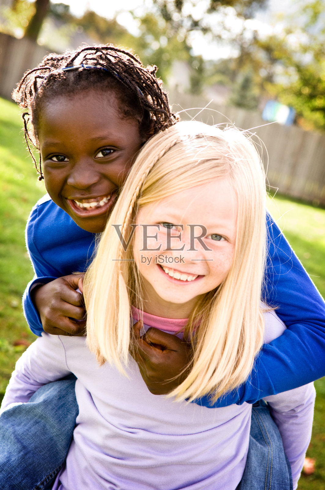 两个快乐的女孩微笑着骑在背上照片摄影图片