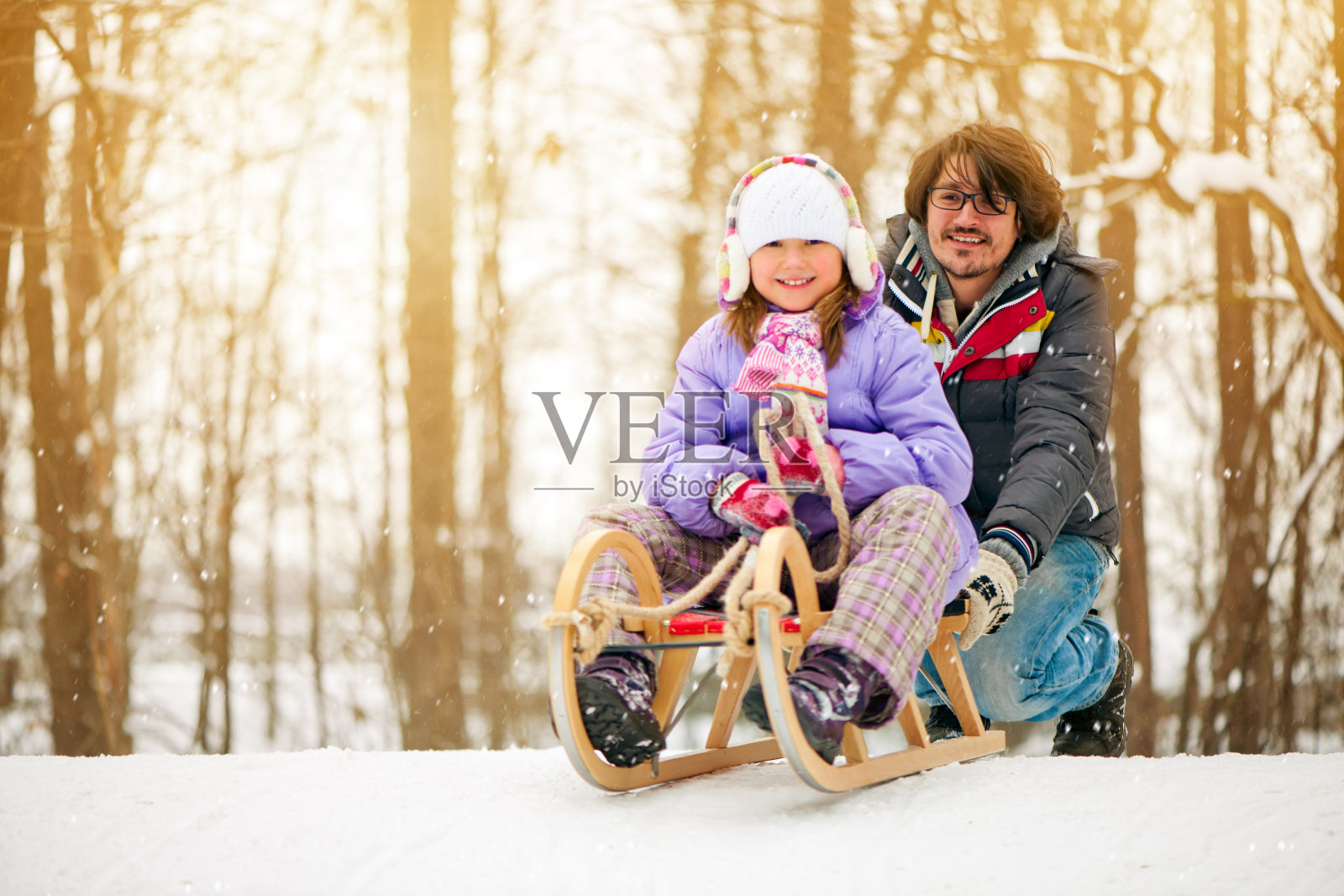 父亲拉着孩子坐雪橇照片摄影图片