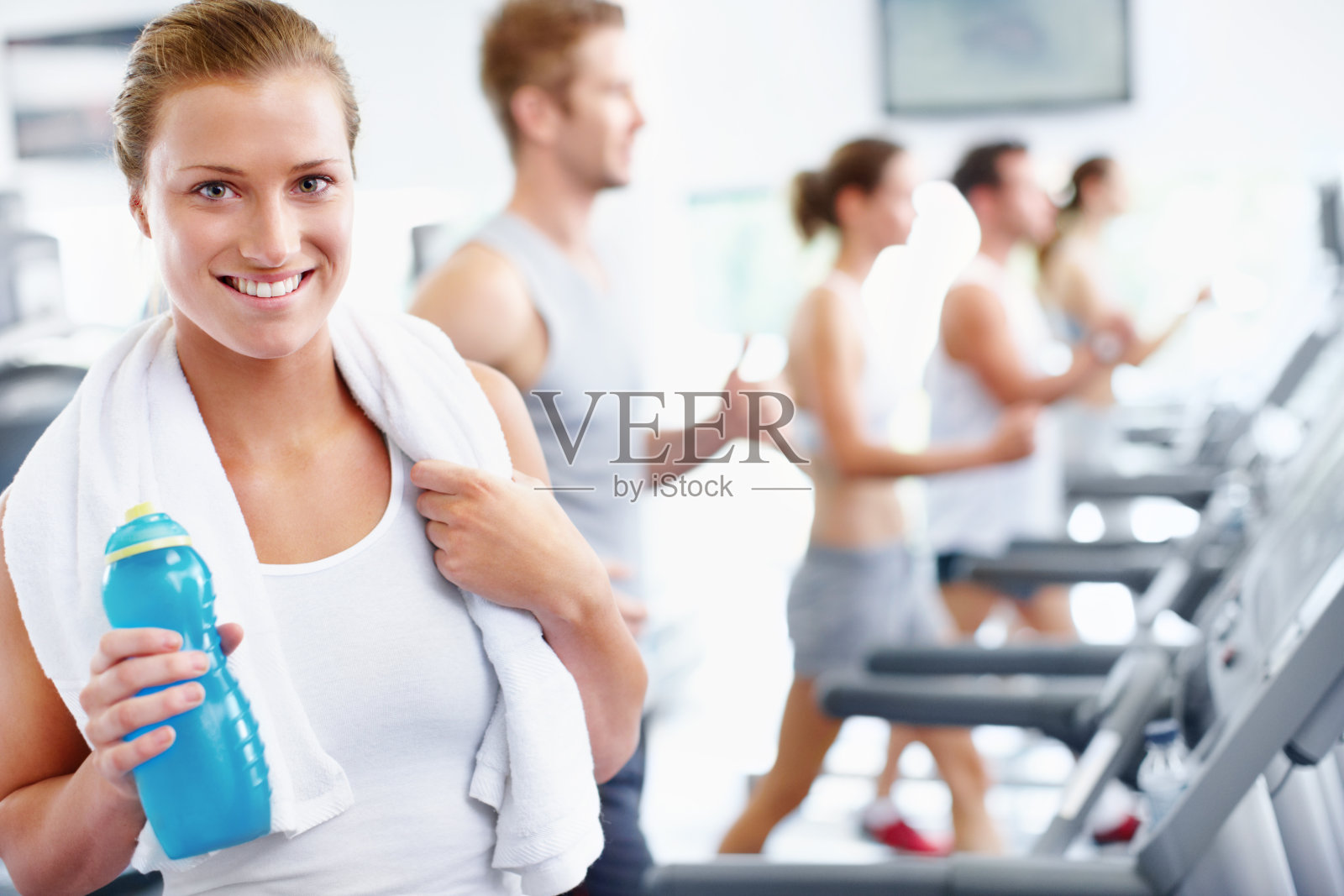 微笑的年轻女子站在跑步机上照片摄影图片