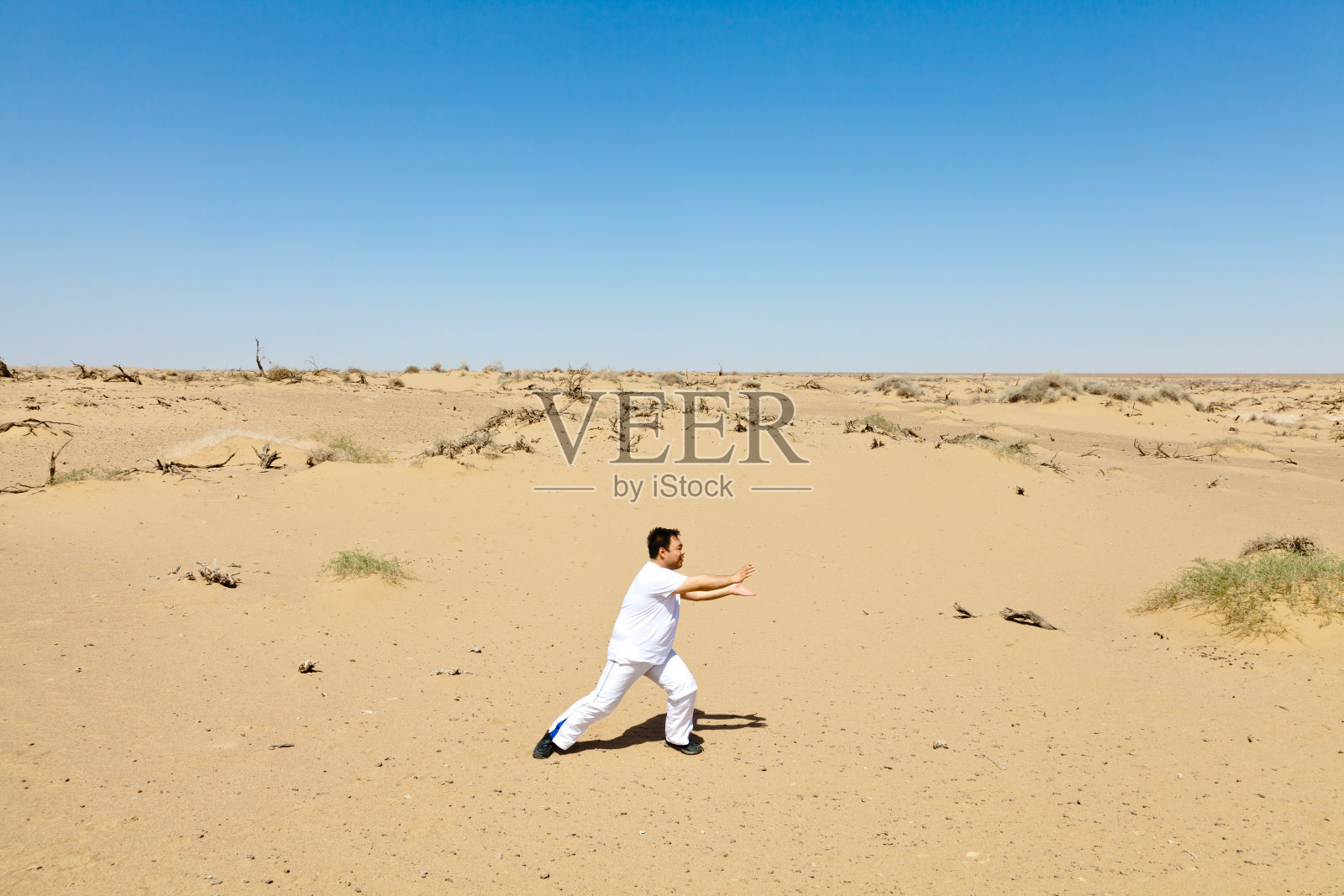 一个年轻人在沙漠里练太极照片摄影图片