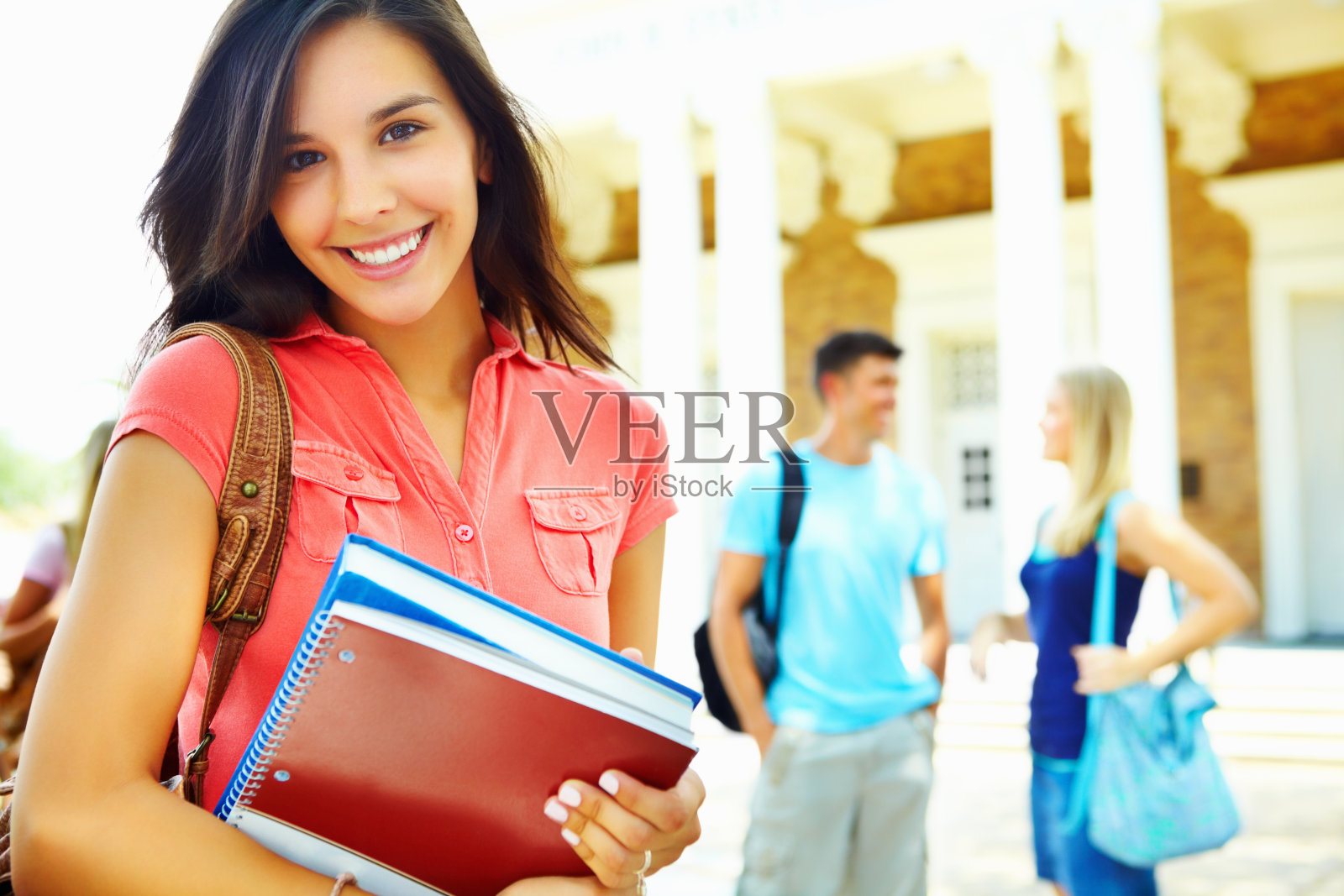 女学生拿着书和包在校园里照片摄影图片
