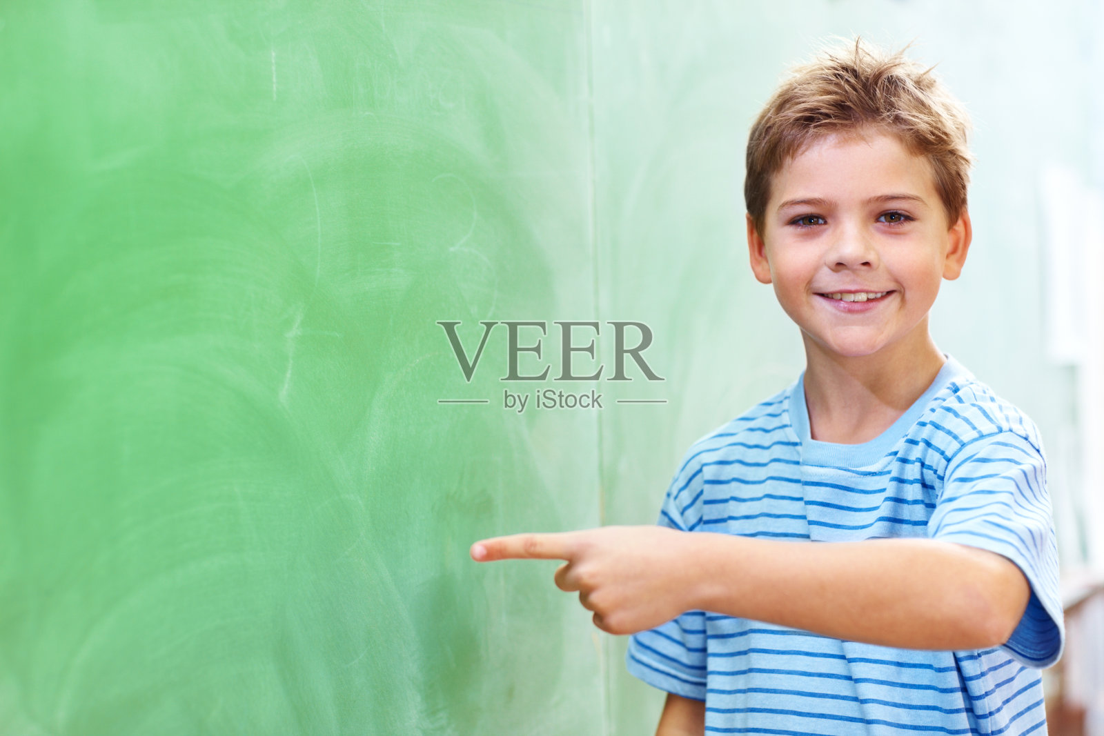 一个小男孩指着黑板照片摄影图片