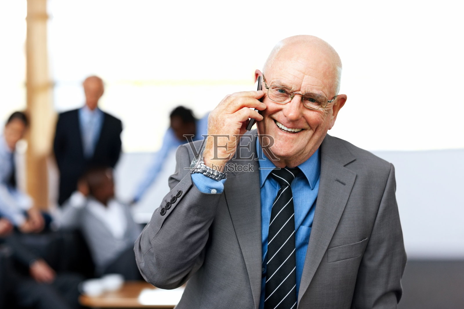 成功的资深商人在办公室用手机聊天照片摄影图片