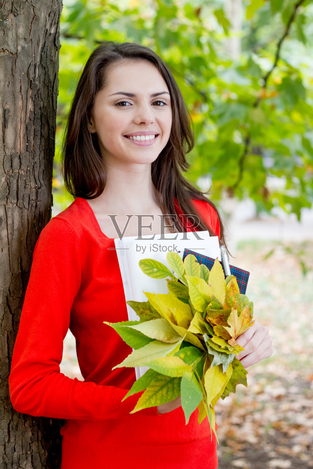 快乐的年轻女子抱着金色的秋叶照片摄影图片
