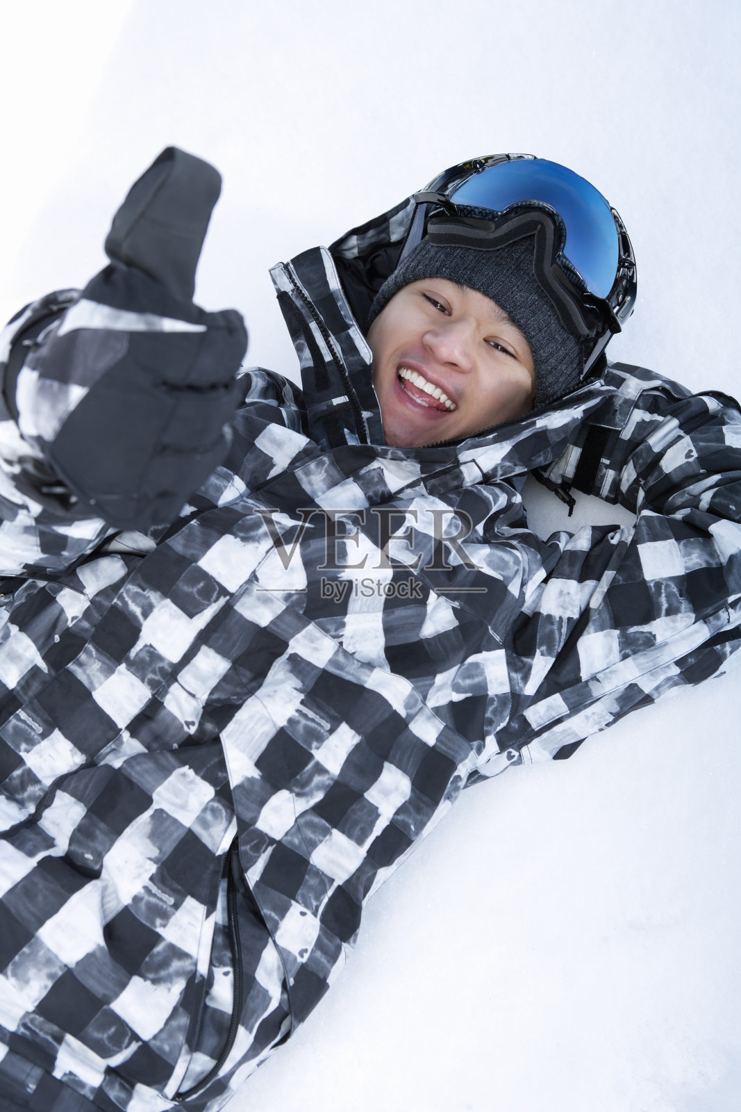快乐的滑雪者躺在雪地上，竖起大拇指照片摄影图片