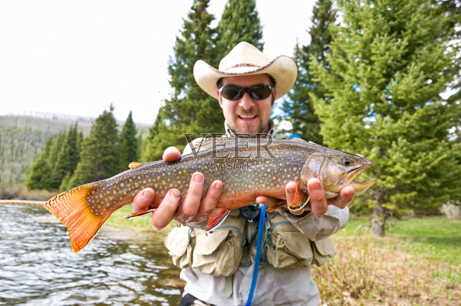 一名男子兴奋地抱着大鳟鱼照片摄影图片