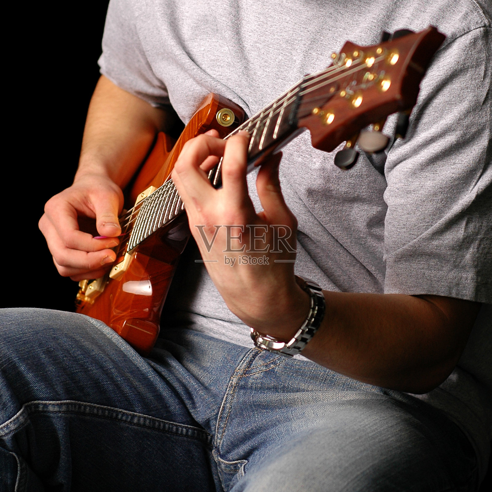 男人坐着弹电吉他，黑色背景照片摄影图片