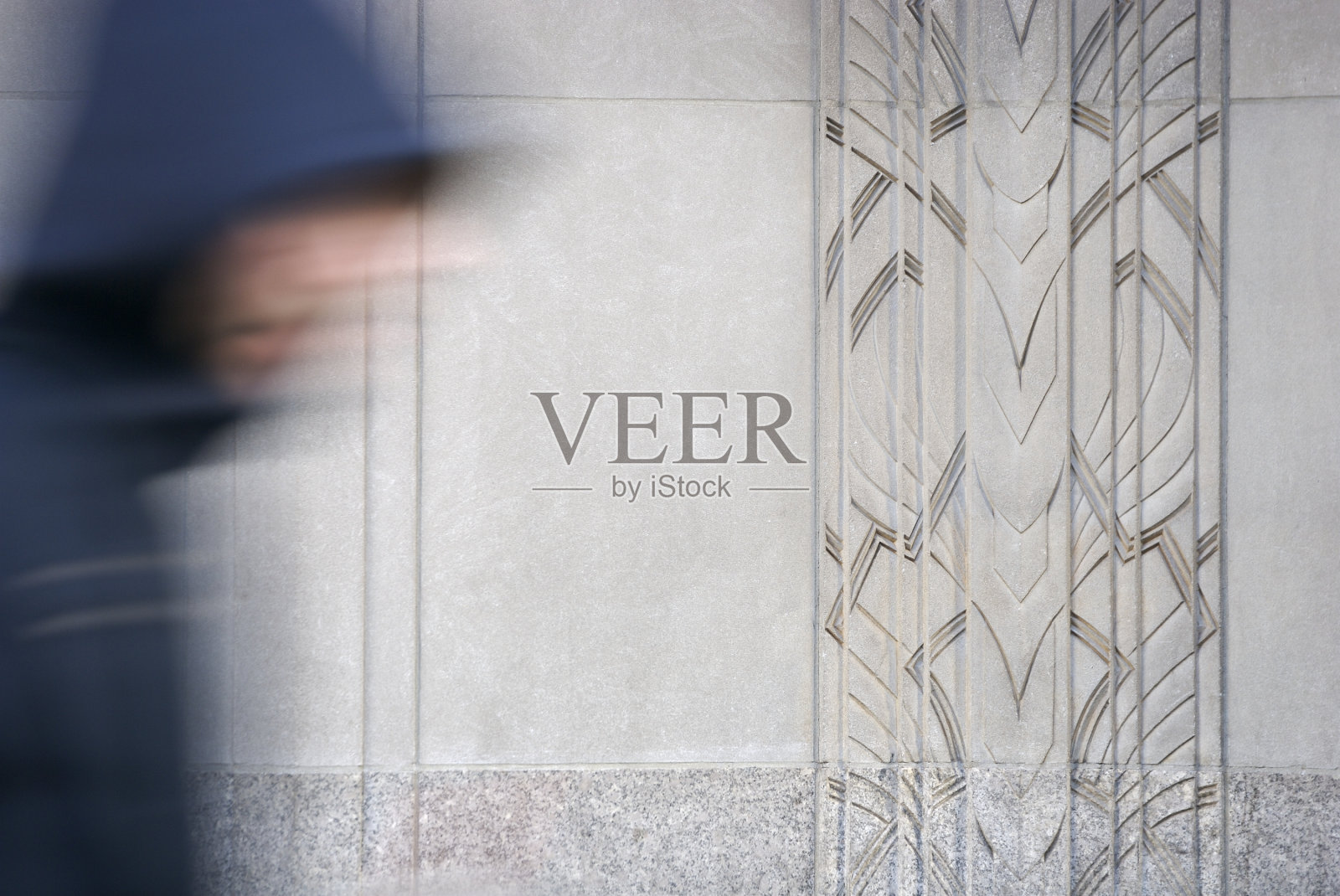 穿黑色连帽运动衫的男人经过装饰艺术墙照片摄影图片