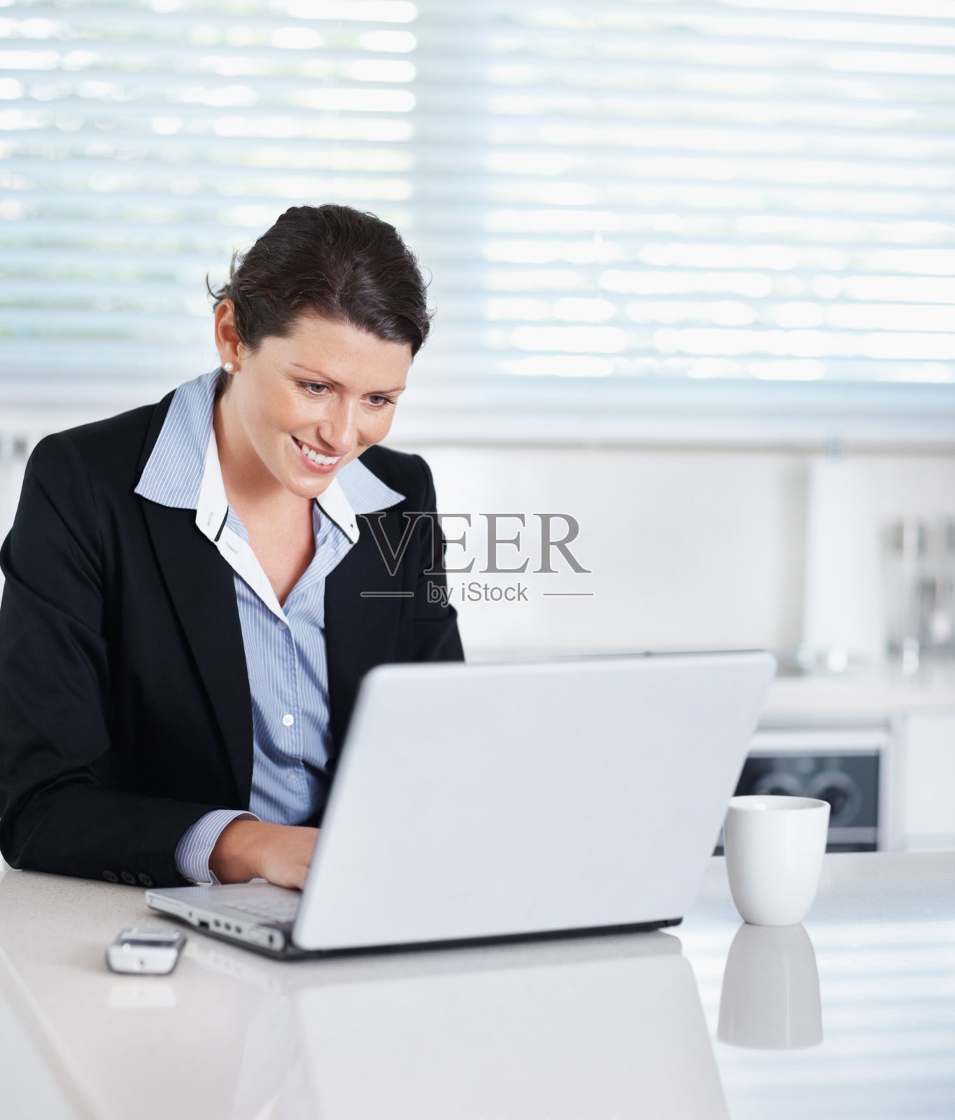 在办公室使用笔记本电脑的微笑女商人照片摄影图片