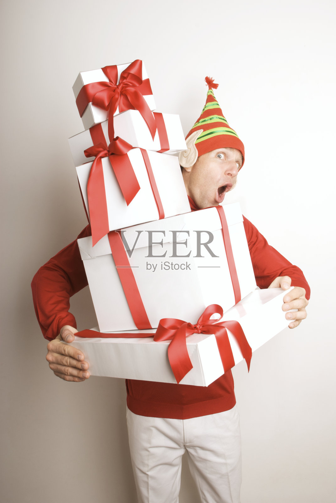 假日精灵男人拿着一叠礼物看起来很惊讶照片摄影图片
