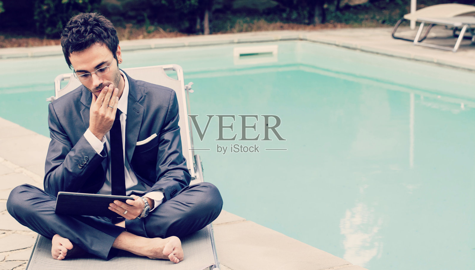 在游泳池附近使用平板电脑的商人照片摄影图片