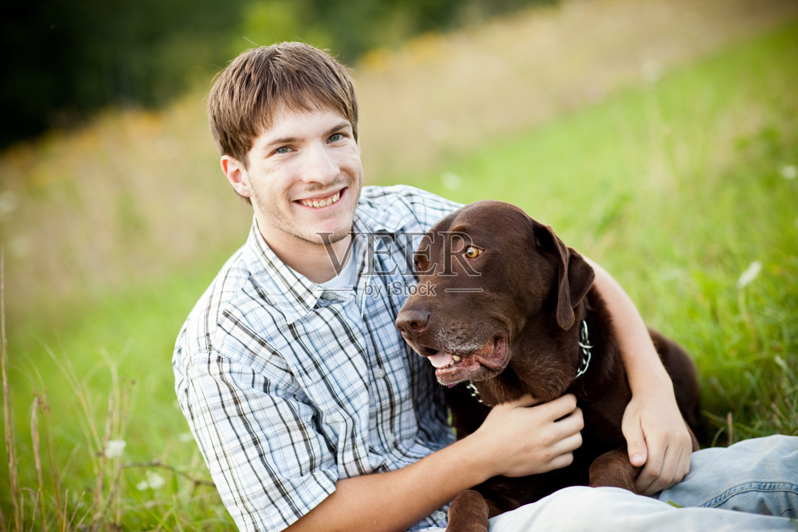十几岁的男孩在户外拥抱他的狗的彩色图像照片摄影图片