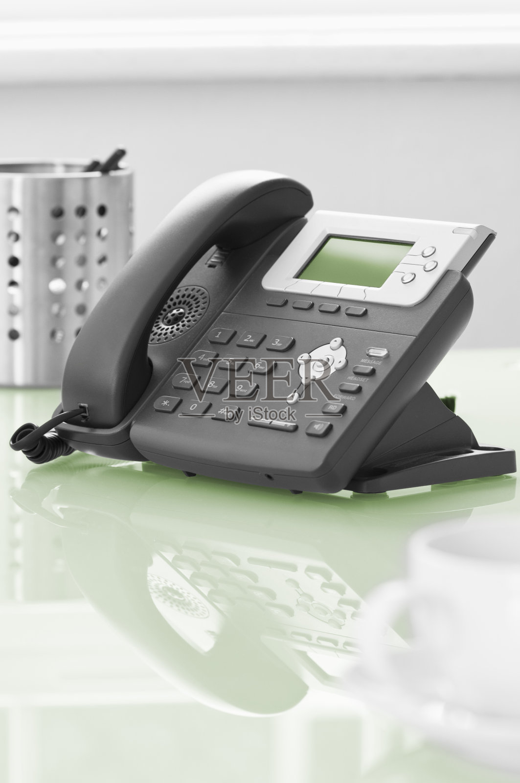现代化的办公室电话放在绿色的玻璃桌上照片摄影图片