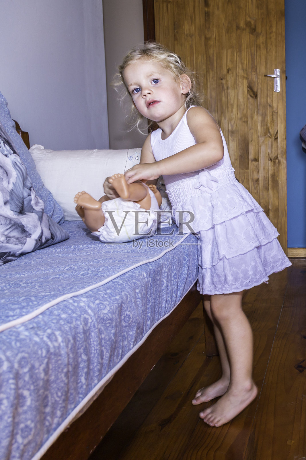 小女孩用尿布给洋娃娃穿衣服照片摄影图片