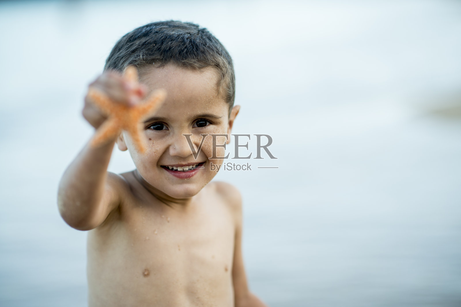 海滩上的可爱男孩和海星照片摄影图片