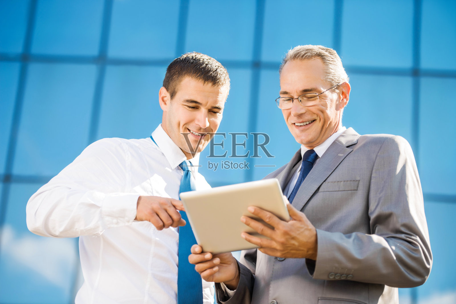 兴高采烈的商人在户外使用触控板。照片摄影图片