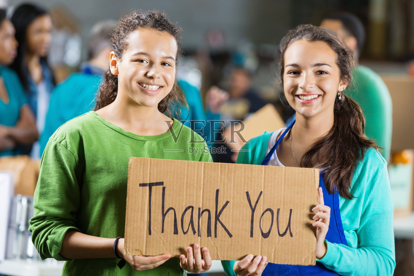 青少年志愿者在社区食物银行举着“谢谢”的牌子照片摄影图片