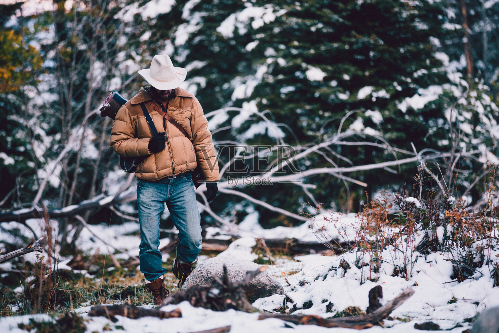 一名男子背着露营装备穿过白雪覆盖的树林照片摄影图片
