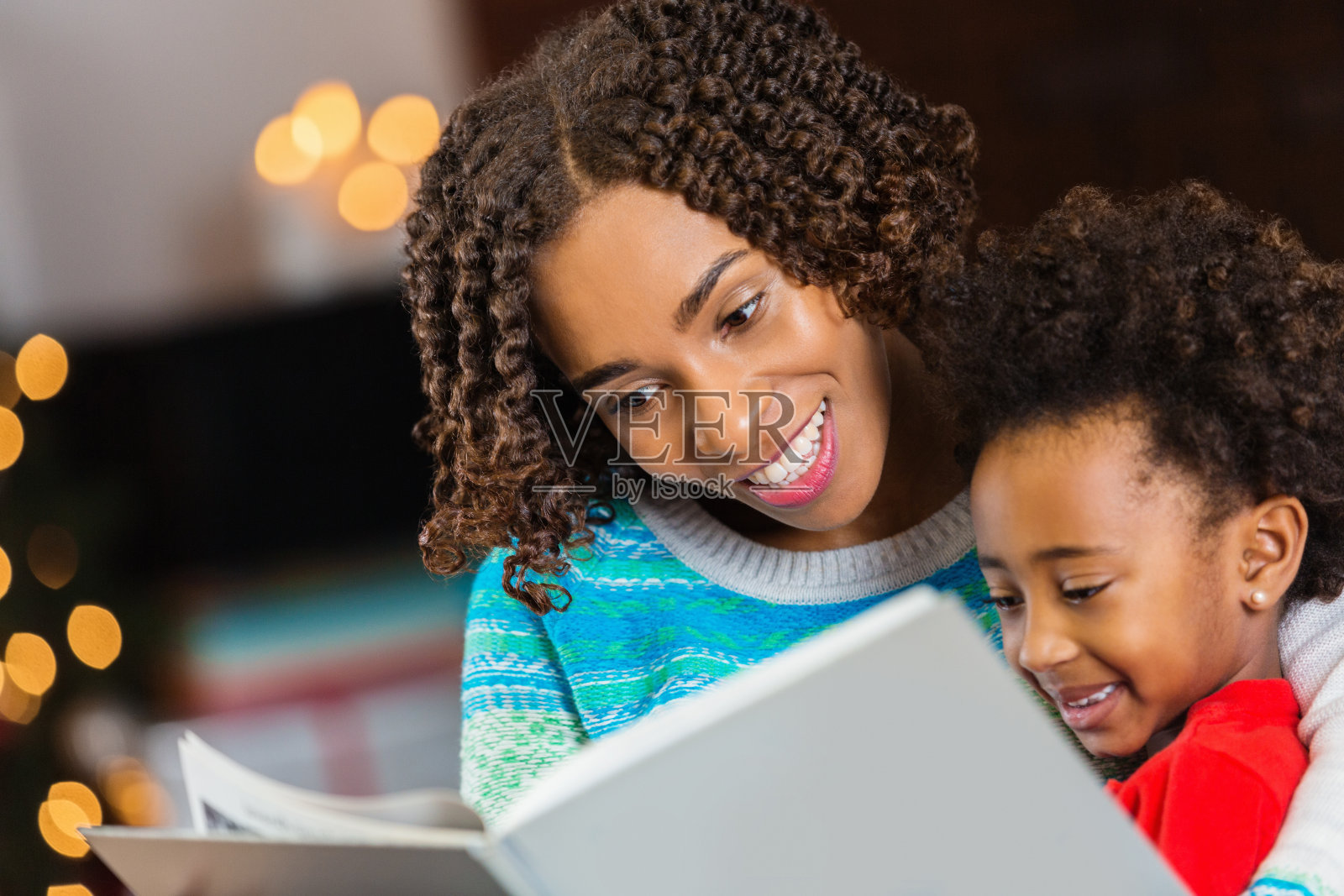 非裔美国妈妈给小女儿读圣诞故事照片摄影图片