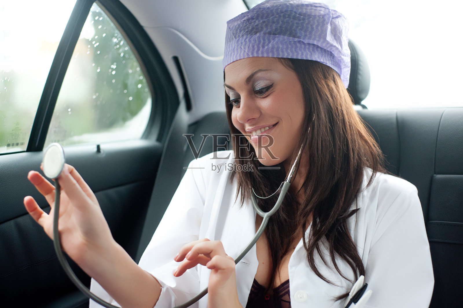 年轻性感的女医生坐在汽车后座上照片摄影图片