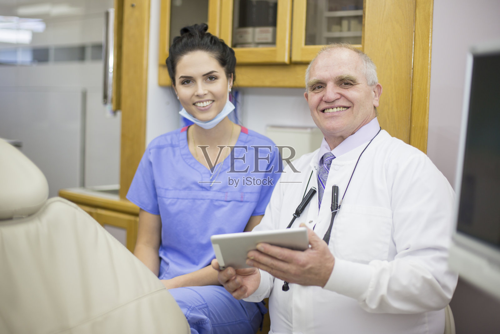 在牙科检查室里的女牙科保健师和男牙医。照片摄影图片