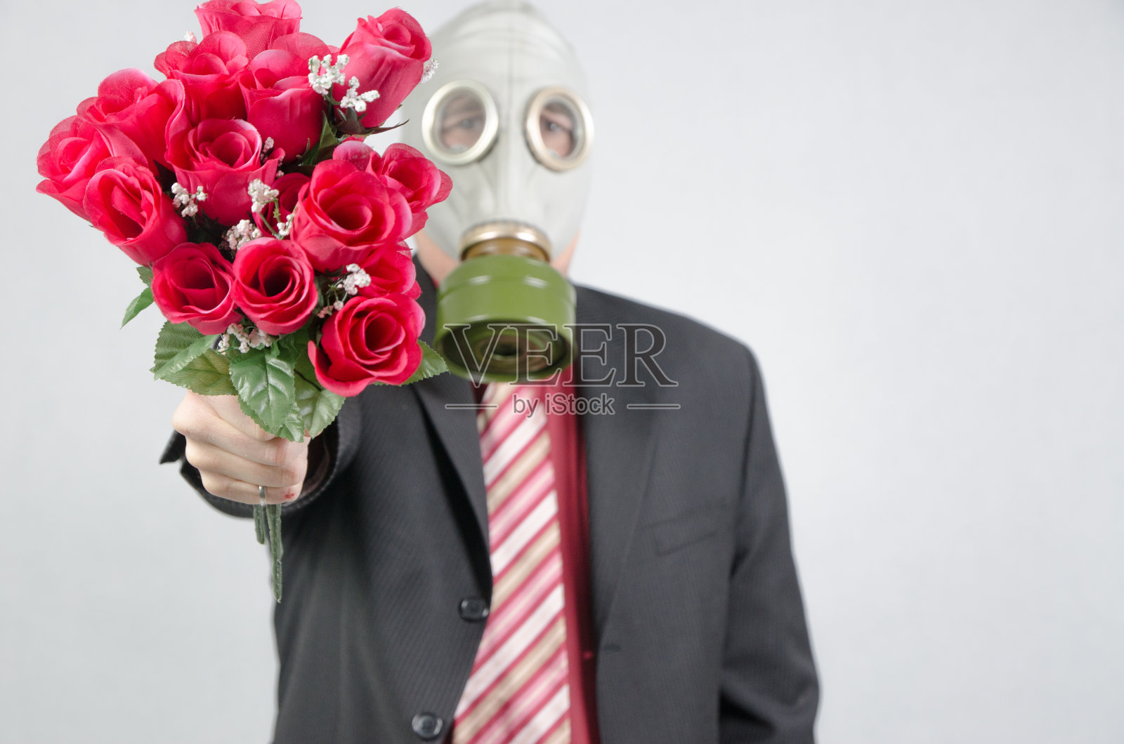 商人戴着防毒面具，手持一束玫瑰照片摄影图片