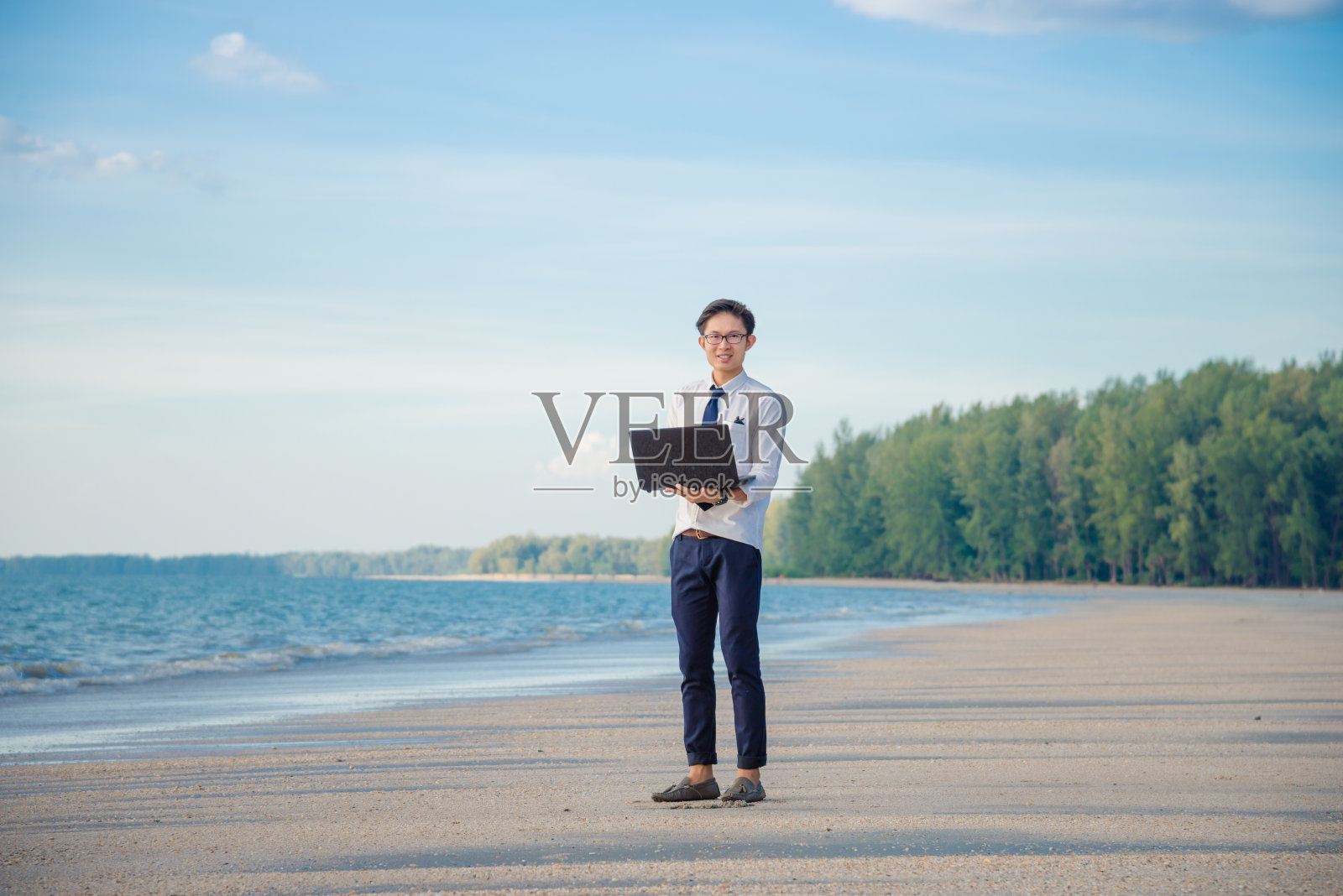 商人工作与笔记本电脑和智能手机的海滩背景照片摄影图片