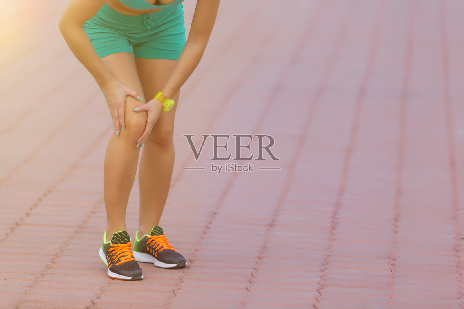 女跑步运动员扶着运动中受伤的膝盖照片摄影图片