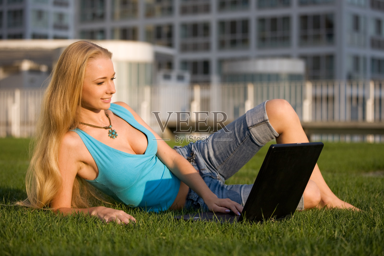 草地上拿着笔记本电脑的女孩照片摄影图片