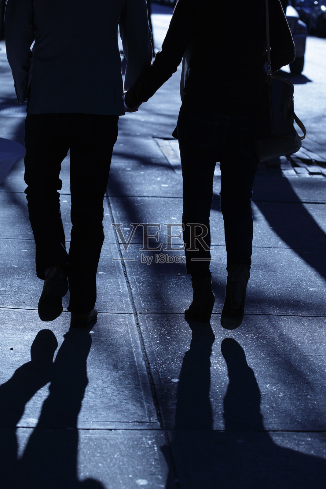 一男一女手牵着手走在蓝夜的阴影里照片摄影图片