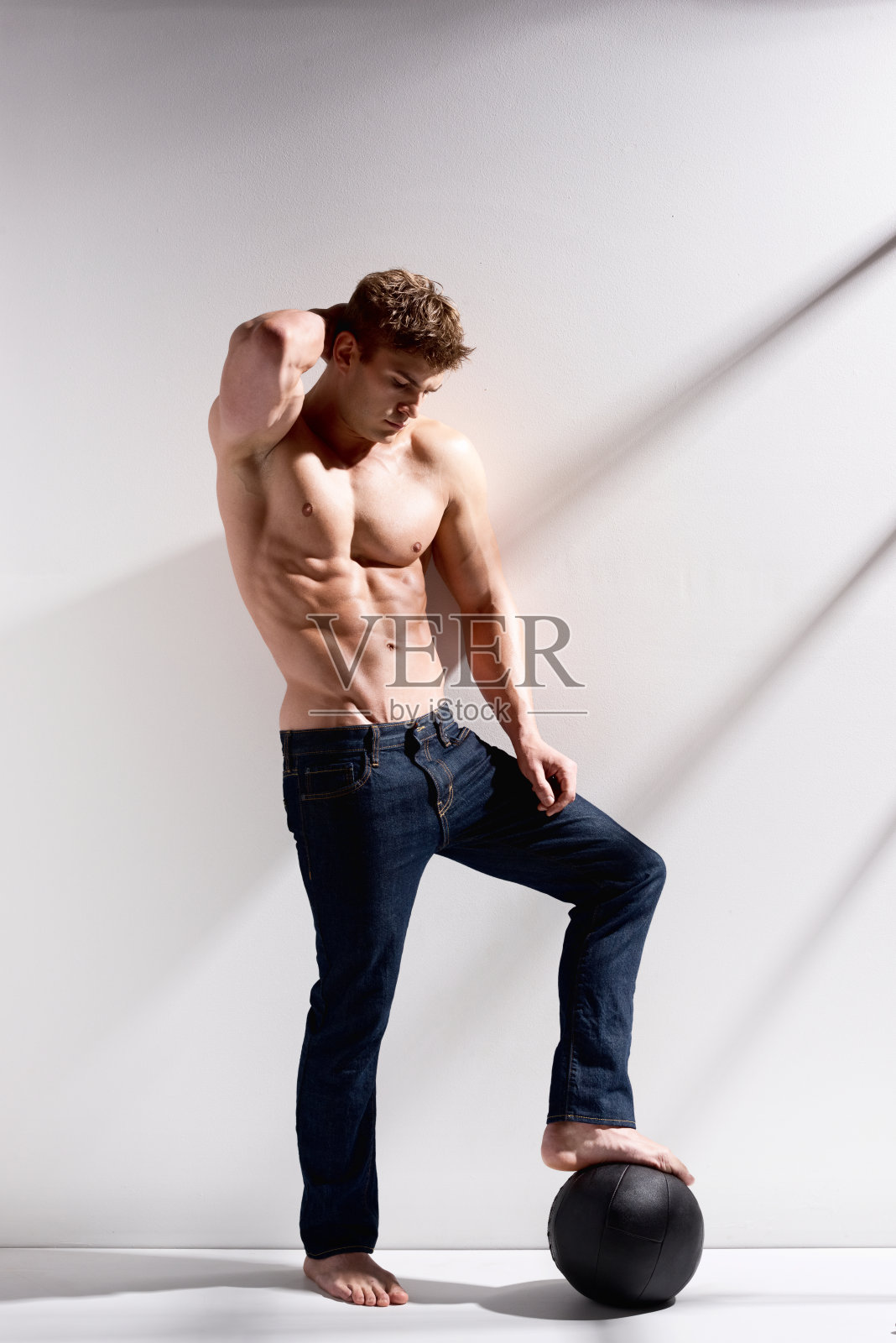 赤膊壮汉站在实心球上照片摄影图片