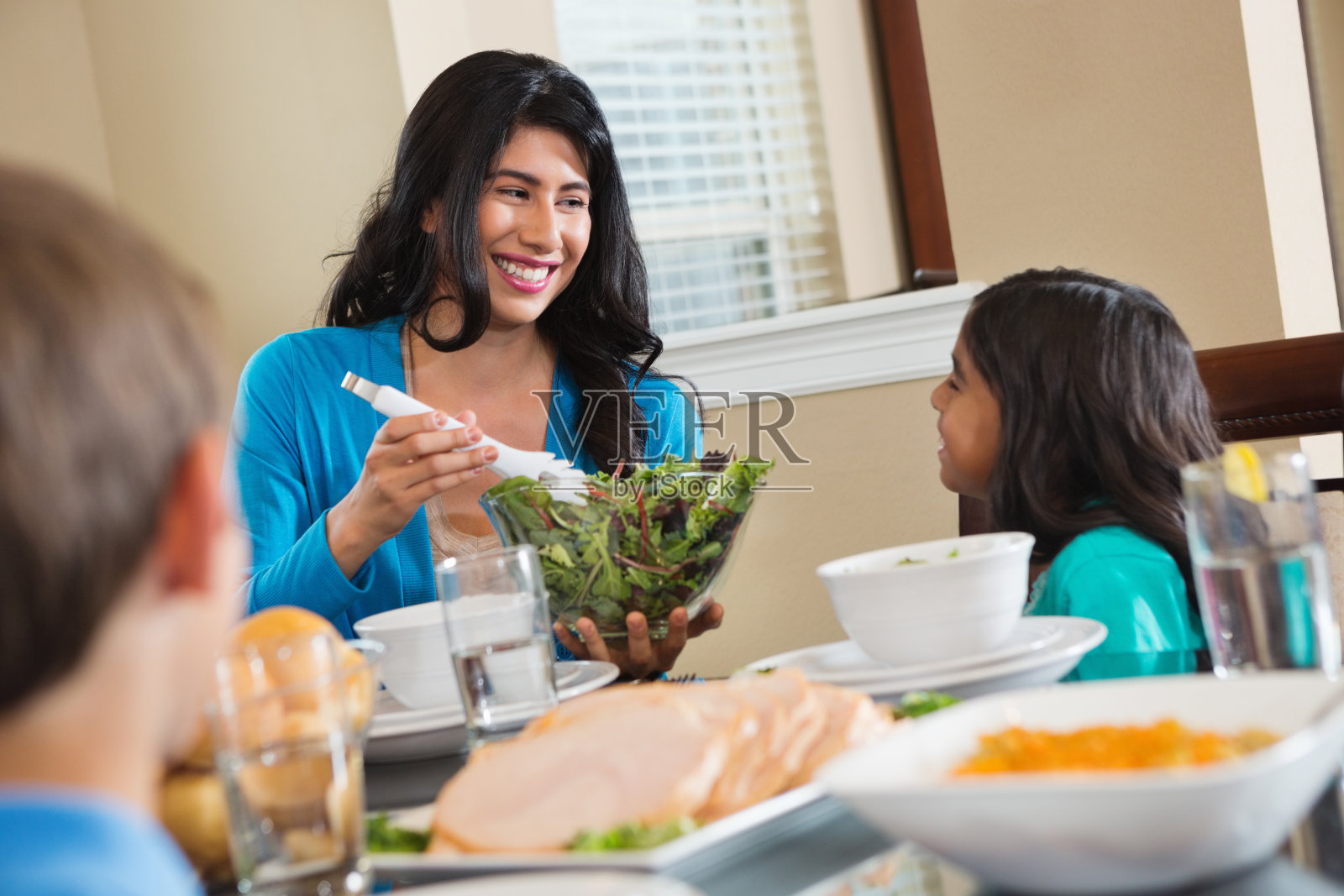 妈妈在餐桌上为她的家人提供健康的食物照片摄影图片