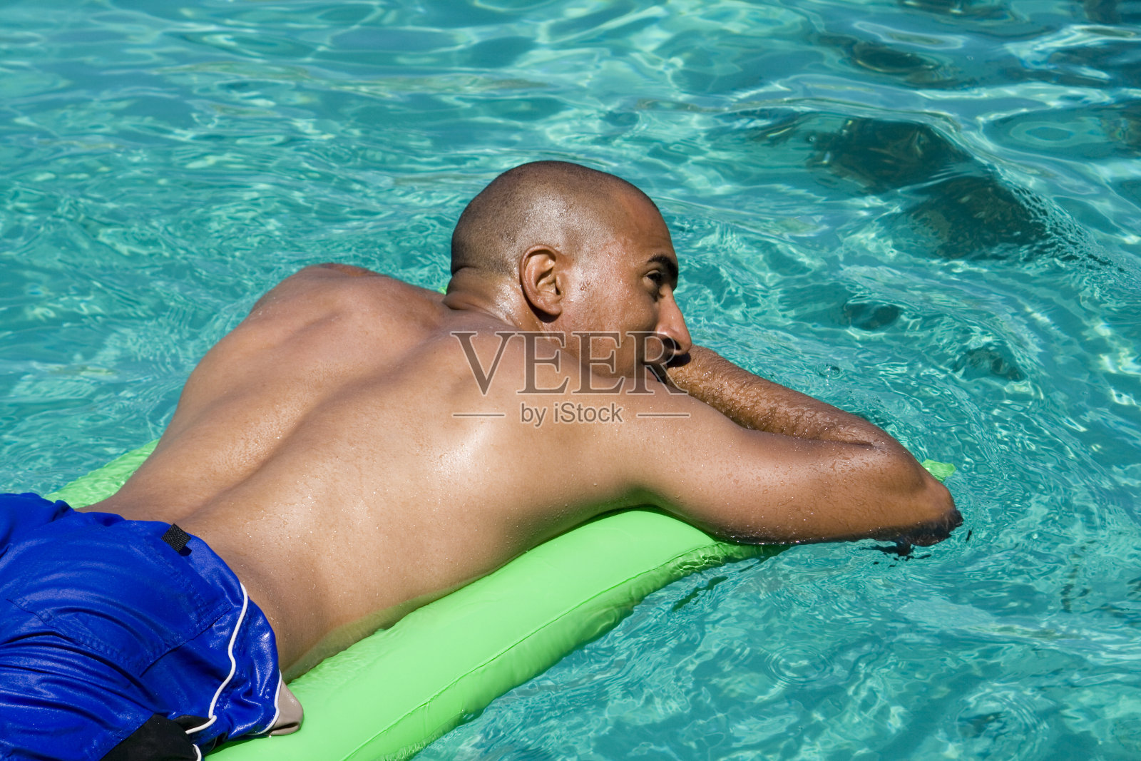 一个年轻人在游泳池的木筏上休息照片摄影图片