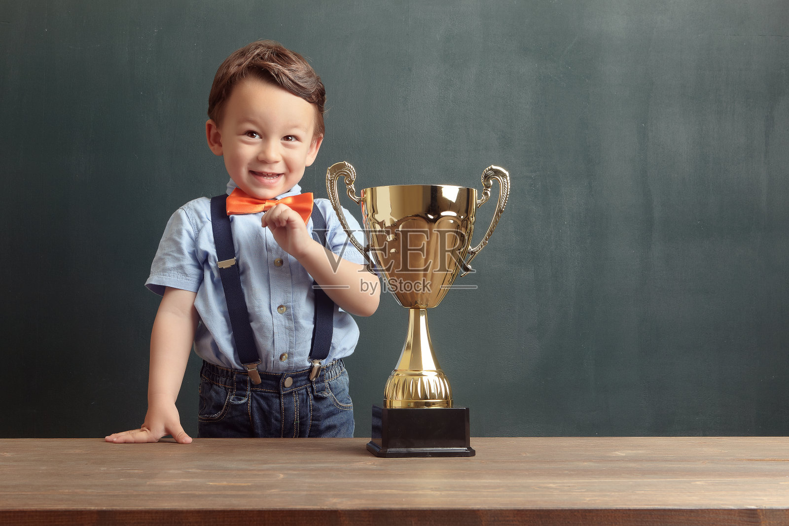 小男孩拿着金杯微笑着照片摄影图片