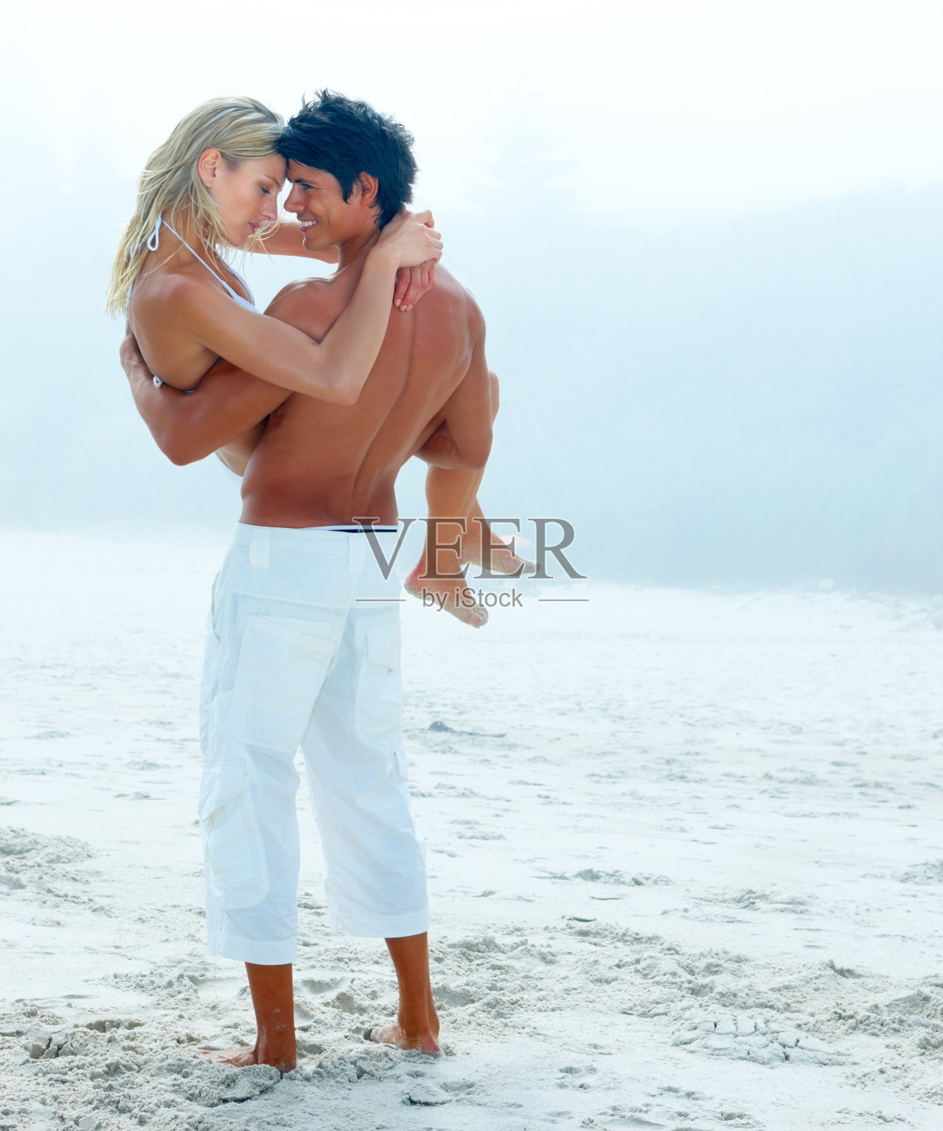 一个年轻人在海滩上抱着他可爱的女朋友照片摄影图片